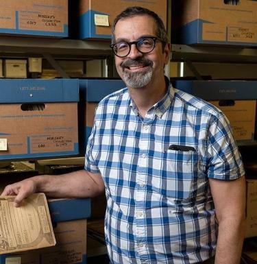 James Cassaro stands in front of a shelf of film archives